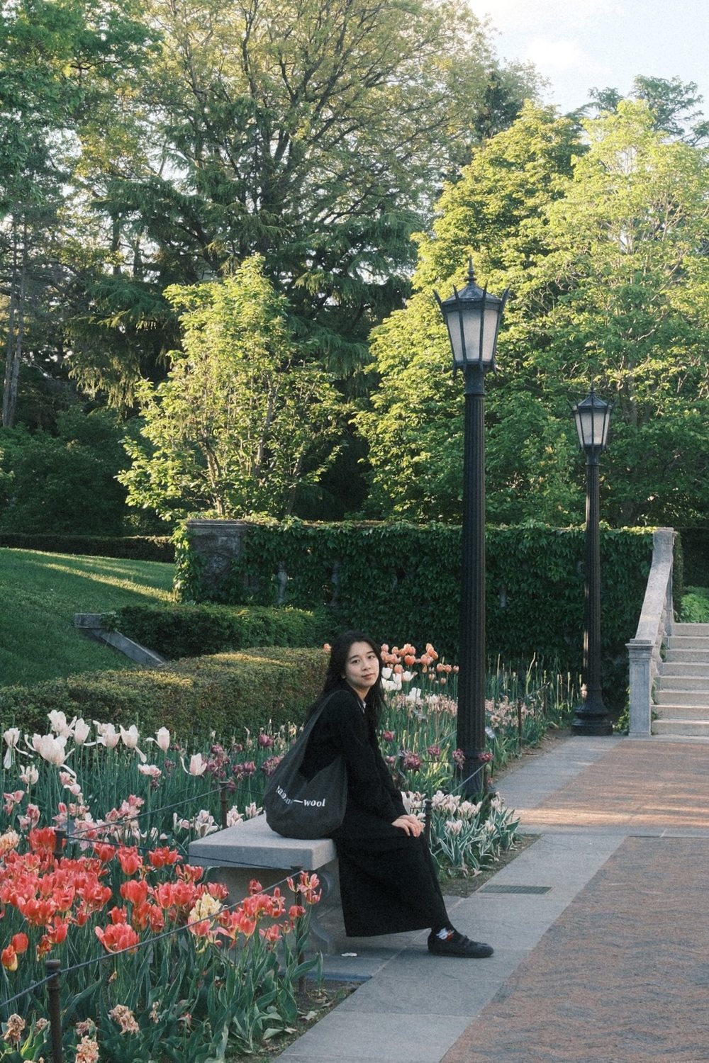 Bridgit Jung sitting on a stone bench beside tulips in a garden